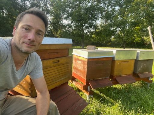 Elmar am Bienenstand mit Bienenvölker im Hintergrund